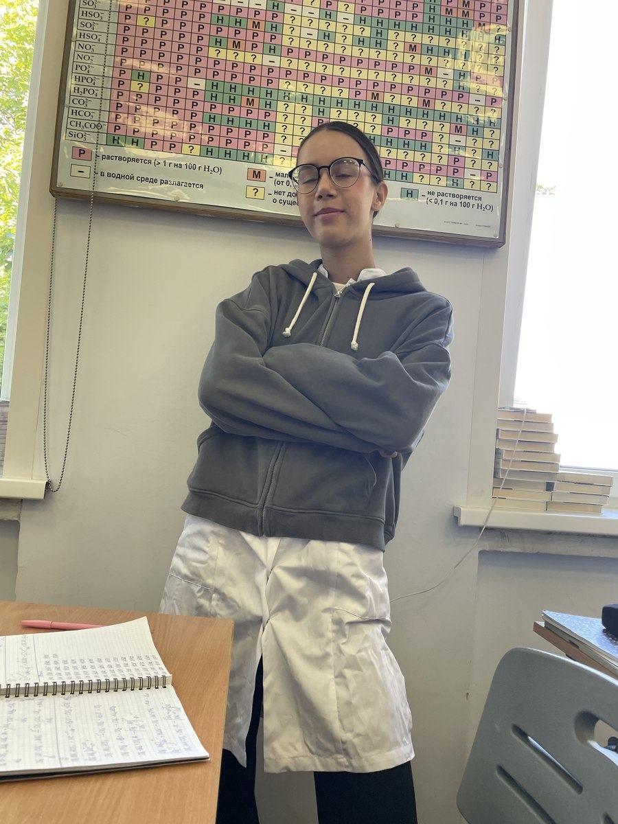 Mariia Miroshnik in a chemistry classroom, next to a solubility chart